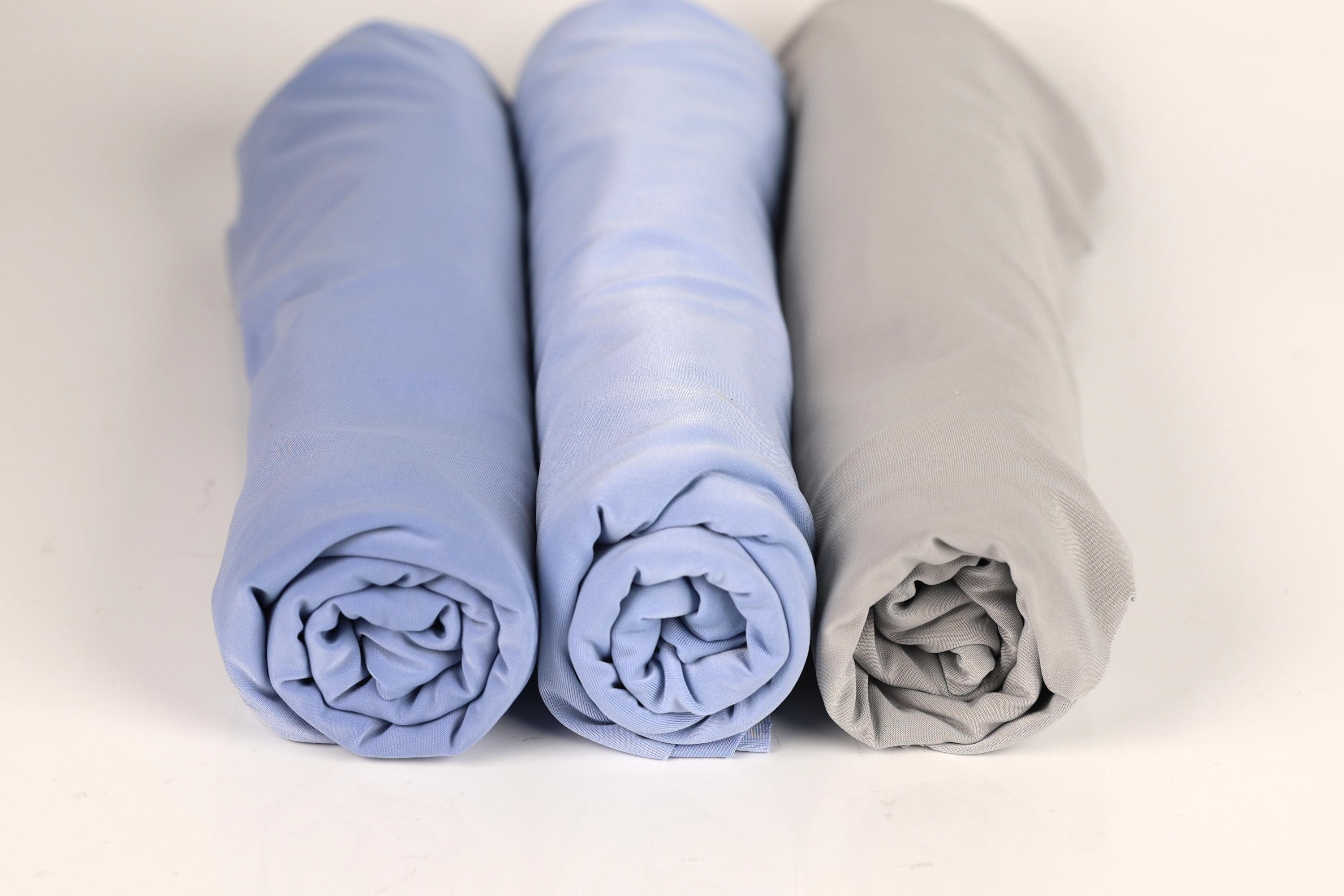 Three rolled-up blue and gray towels are arranged in a row on a white background.