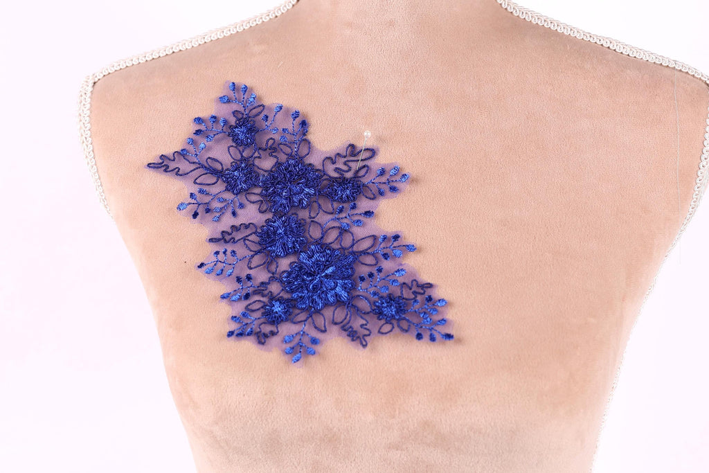 a close-up view of a mannequin torso with a decorative blue floral embroidery on the skin.
