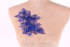a close-up view of a mannequin torso with a decorative blue floral embroidery on the skin.