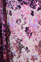 a close-up view of a fabric with a vibrant, multicolored pattern. The fabric appears to be a blend of pink, purple, and black sequins, creating a visually striking and eye-catching design. The pattern is intricate and detailed, with the sequins adding a touch of sparkle and texture to the overall appearance.