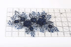 a close-up view of a piece of fabric with a floral pattern, placed on a ruler for scale.