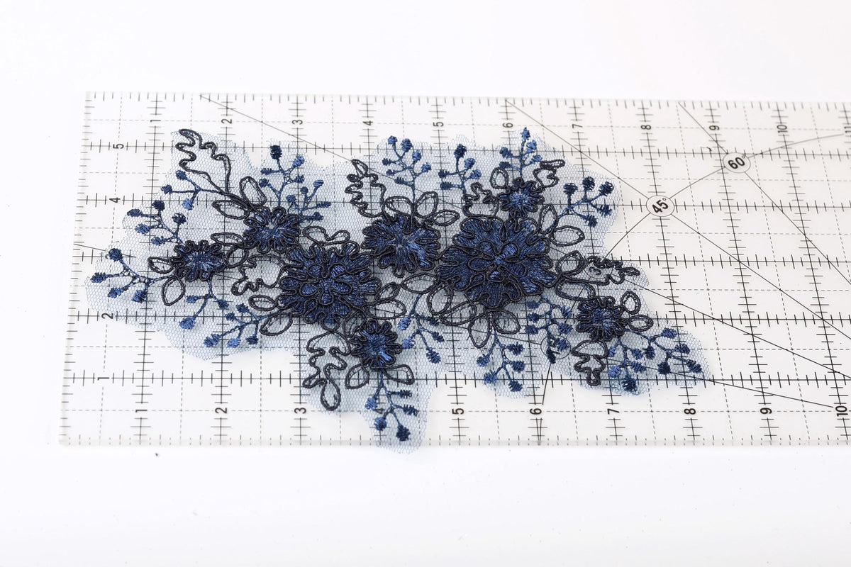 a close-up view of a piece of fabric with a floral pattern, placed on a ruler for scale.