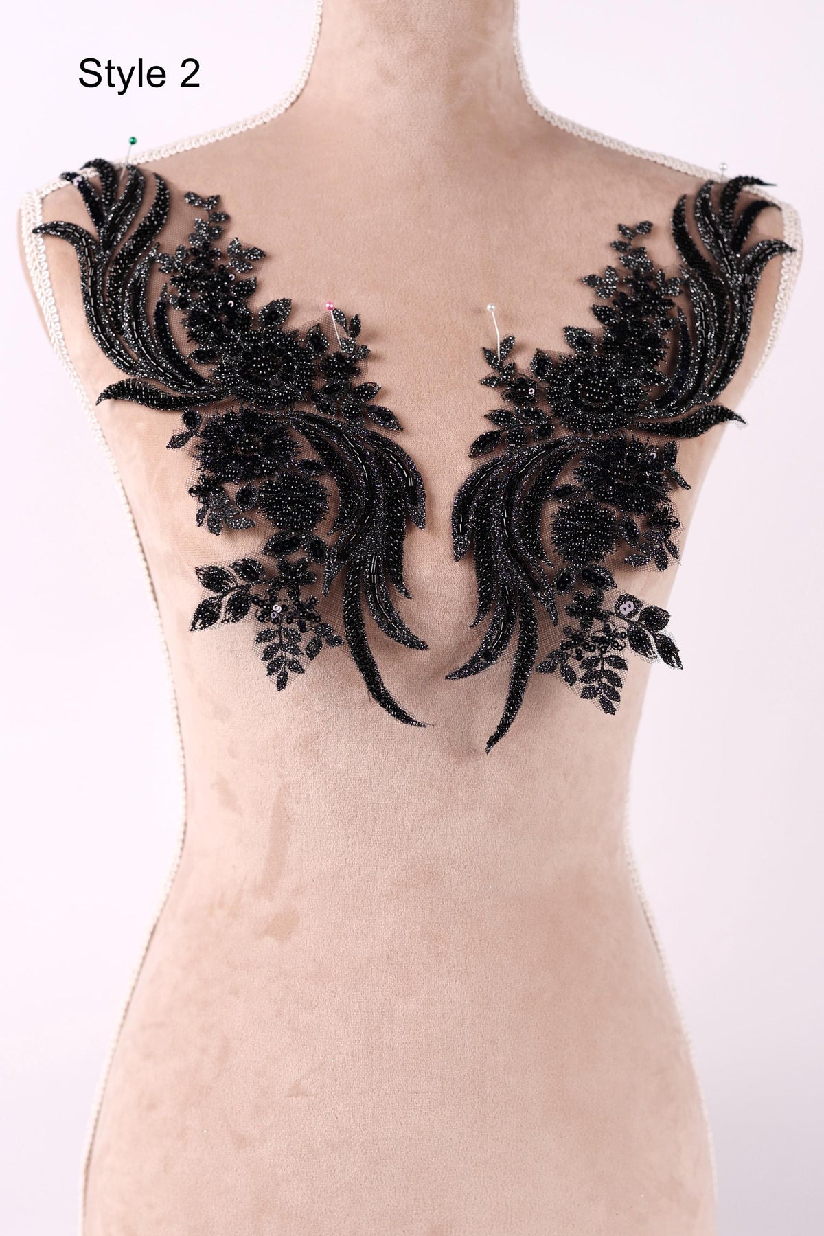 A mannequin wearing a dress with black lace appliques on the shoulders.