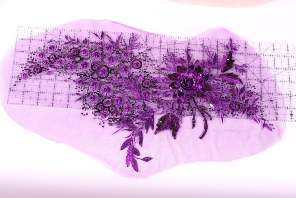 a close-up view of a purple floral design on a piece of fabric, with a ruler placed on top of it to measure the size.
