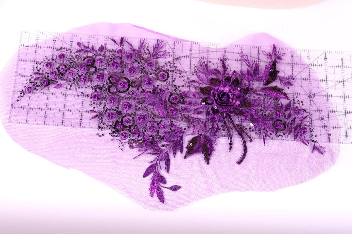 a close-up view of a purple floral design on a piece of fabric, with a ruler placed on top of it to measure the size.