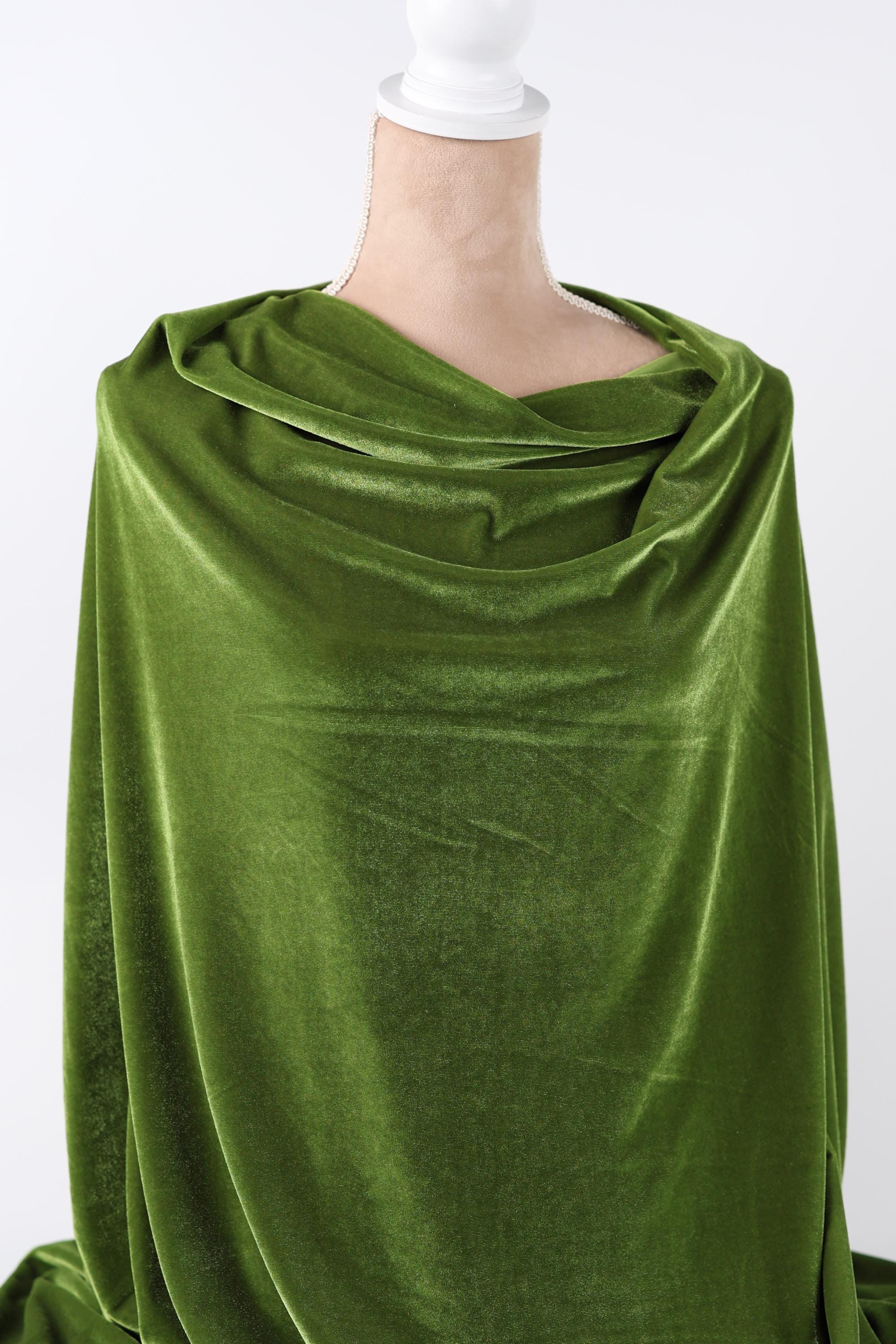 A close-up view of a green velvet fabric, with a white object partially visible in the background.