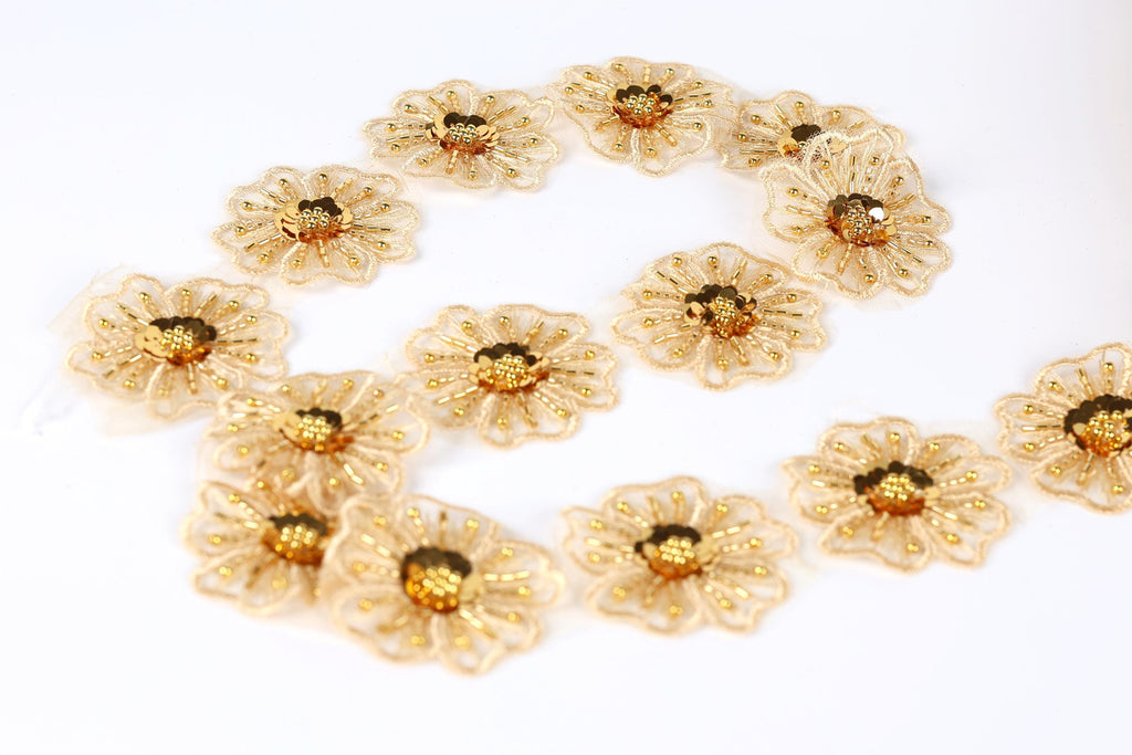 a collection of gold-colored, intricately designed flowers arranged in a circular pattern on a white background.