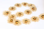 a collection of gold-colored, intricately designed flowers arranged in a circular pattern on a white background.