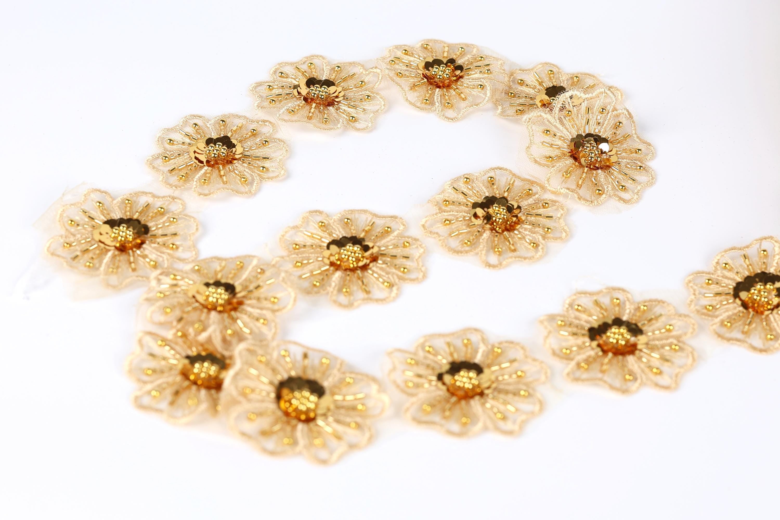 a collection of gold-colored, intricately designed flowers arranged in a circular pattern on a white background.