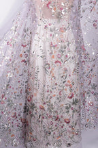 a close-up view of a delicate, intricately embroidered fabric with a floral pattern. The fabric appears to be made of sheer material, allowing the colorful flowers and leaves to be clearly visible. The image does not contain any text or other discernible objects, and the focus is solely on the detailed embroidery and the fabric's texture.