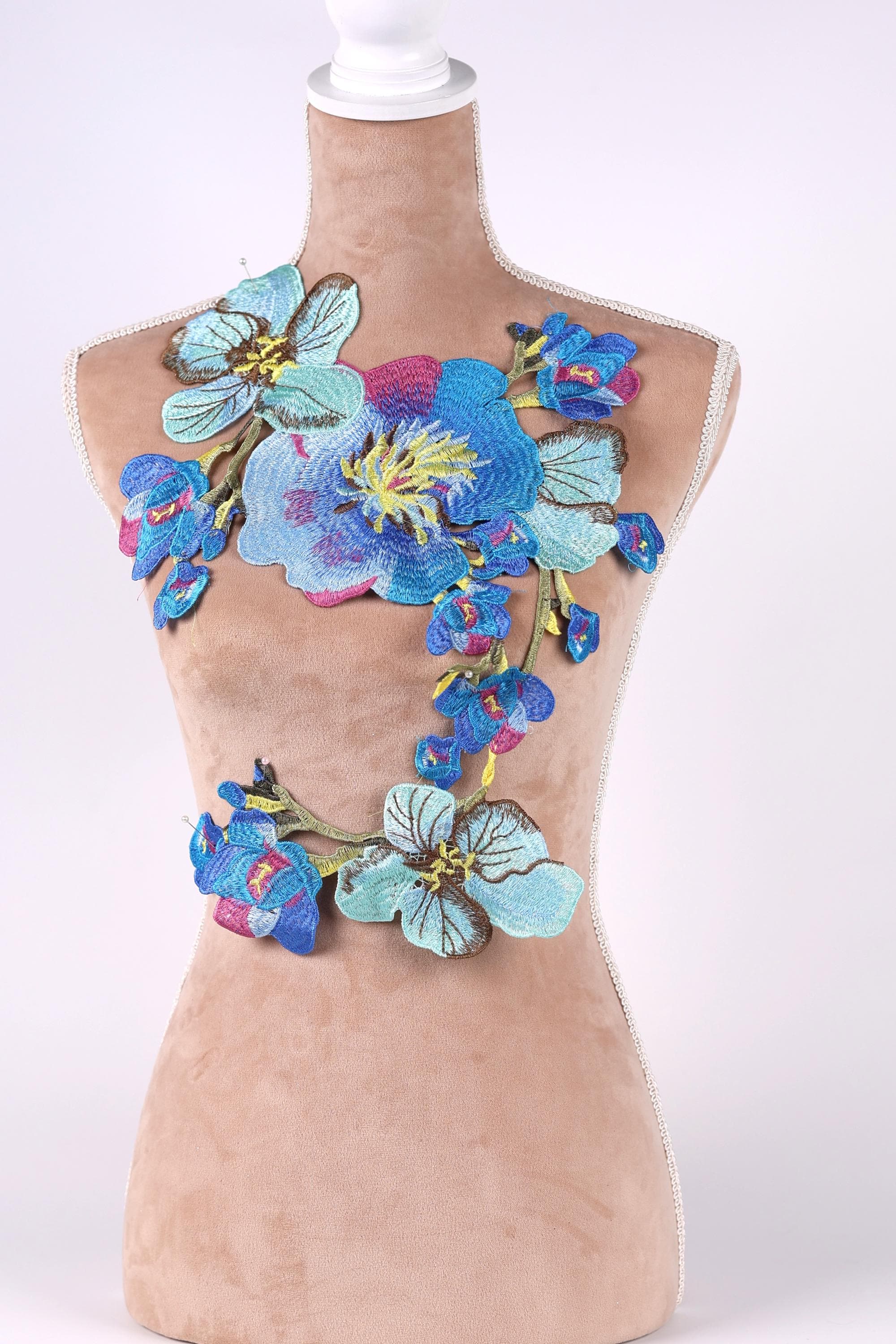A mannequin wearing a dress with a floral embroidered design on the bust area.