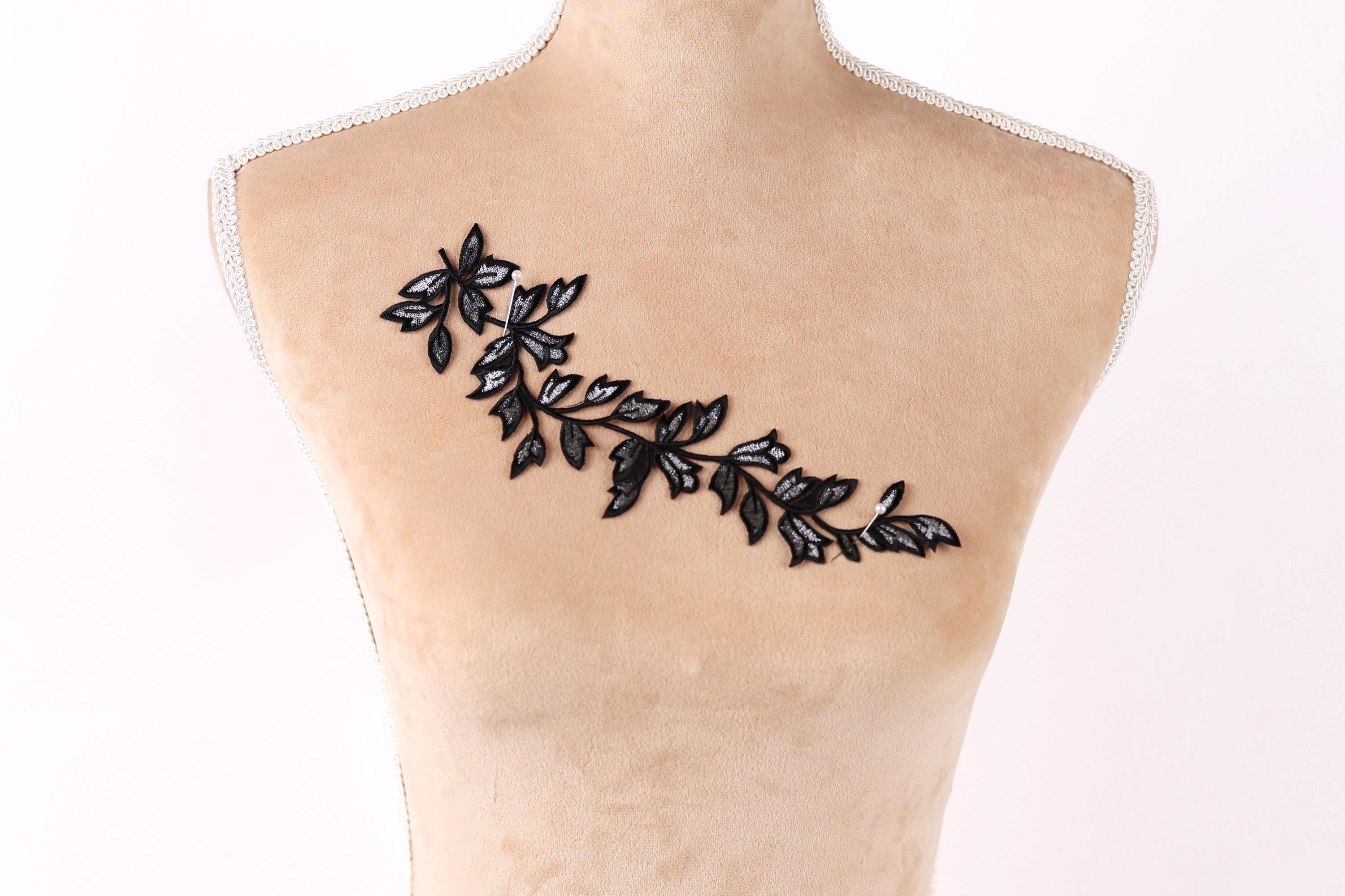 a mannequin torso with a black and white embroidered leaf design on it.