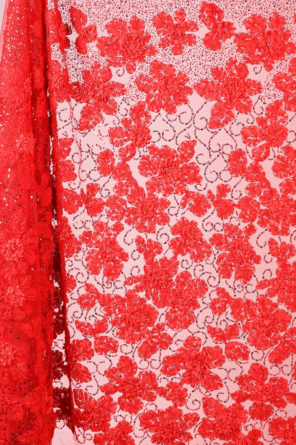 a close-up view of a red fabric with a floral pattern. The fabric appears to be made of a sheer material, with a repeating pattern of red flowers and leaves. The fabric is displayed in a vertical orientation, with the left side of the fabric partially visible.