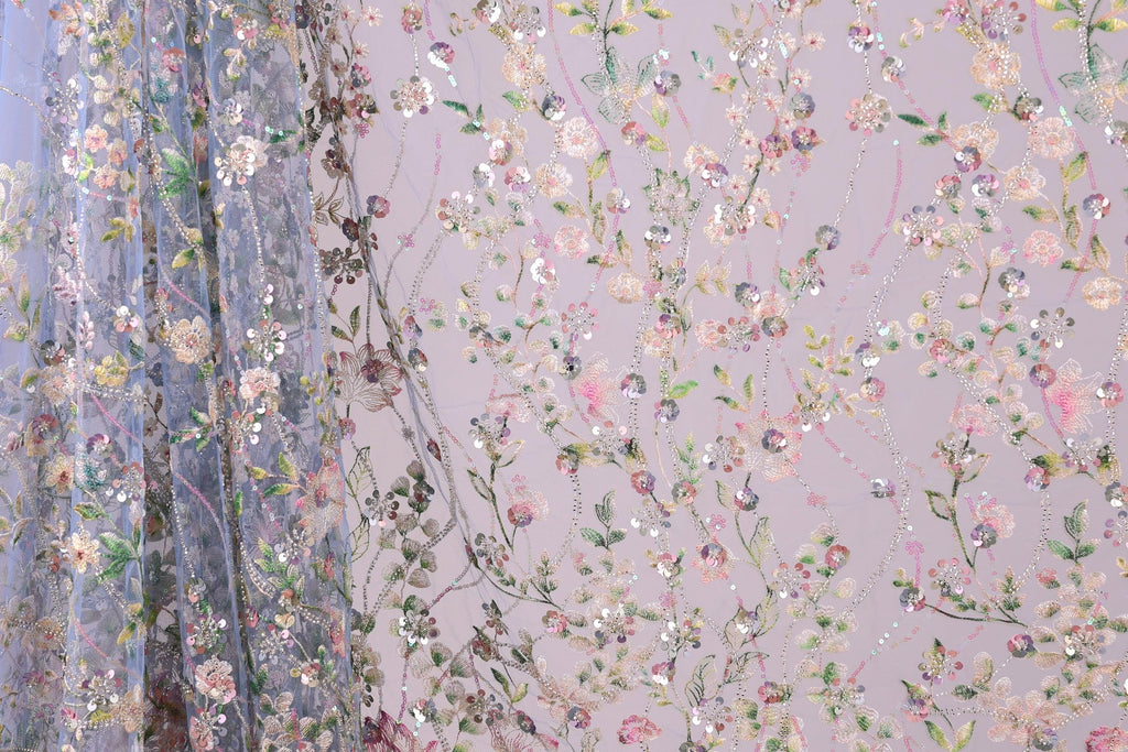 a close-up view of a fabric with a floral pattern, including various shades of pink, green, and white flowers and leaves. The fabric appears to be made of a sheer material, giving it a delicate and airy appearance. The pattern is intricate and detailed, with the flowers and leaves arranged in a way that creates a visually appealing and textured design.