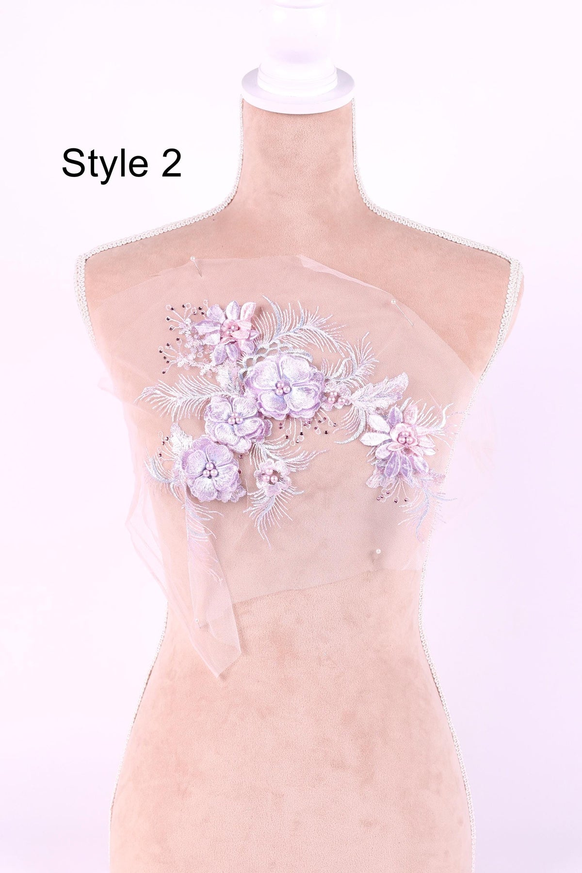 A mannequin with a floral embroidered design on its chest, featuring a variety of pink and white flowers.