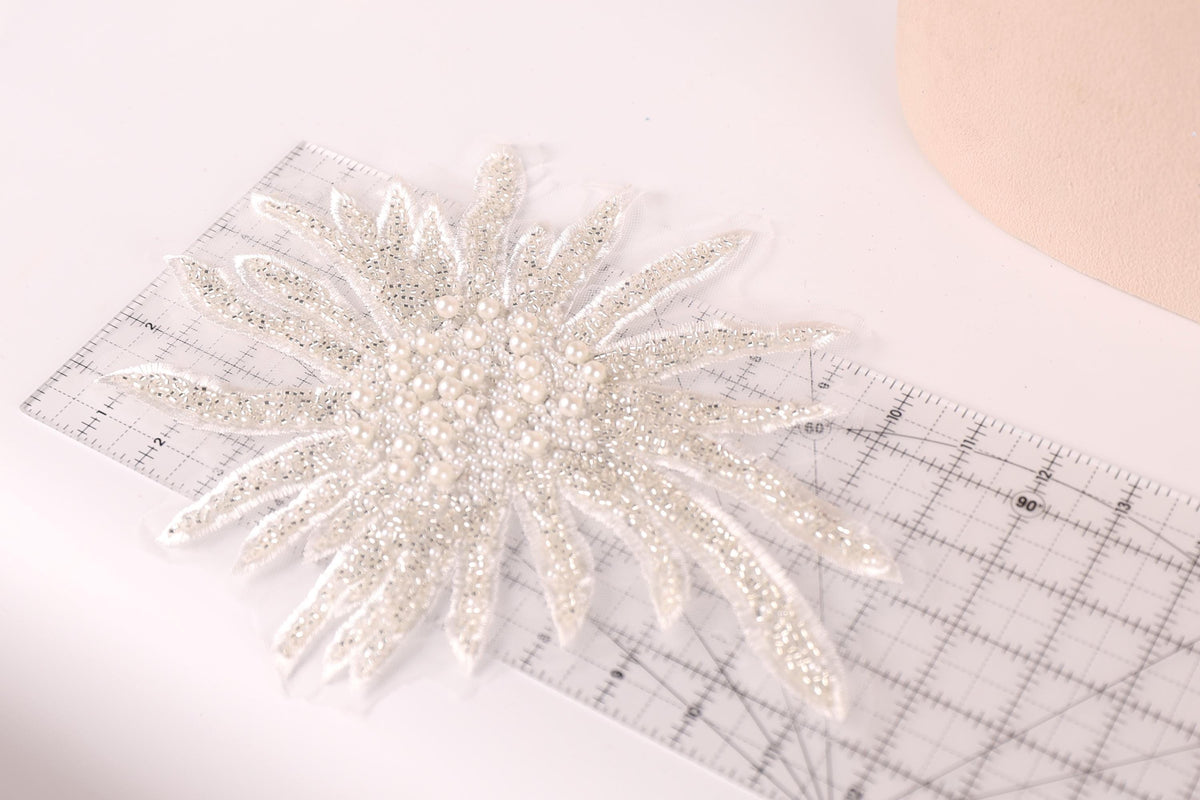 a close-up view of a decorative piece with a floral pattern, placed on a ruler for scale.