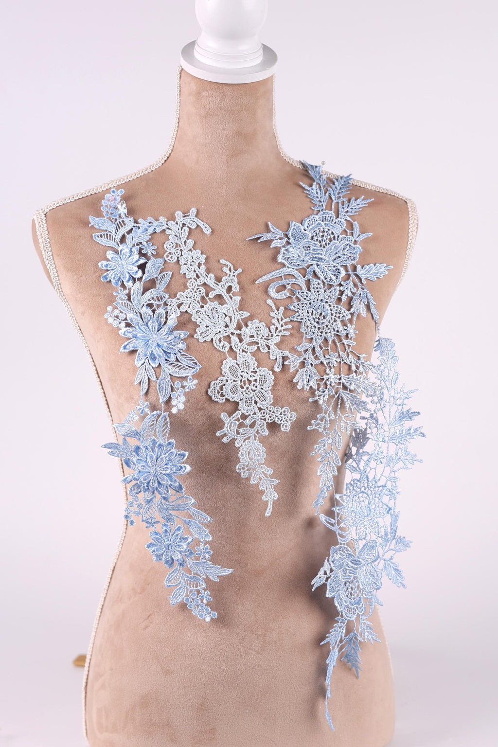 A mannequin wearing a dress with delicate blue lace appliques on the bust area.