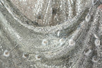 The image is a close-up of a silver sequin fabric with a floral pattern.
