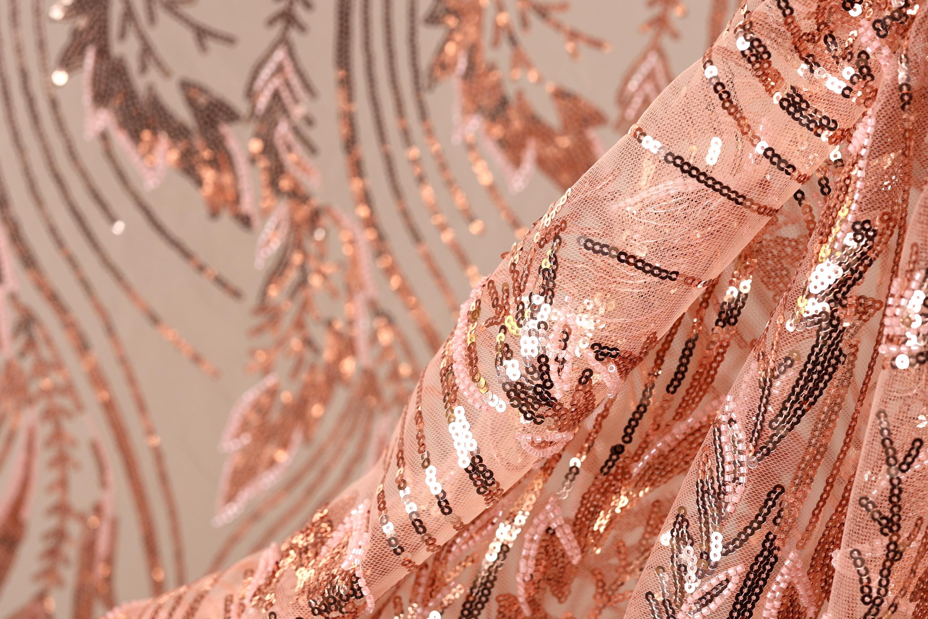 a close-up view of a fabric with a pink and black sequined pattern. The fabric appears to be made of sheer material, with the sequins arranged in a decorative and intricate manner.