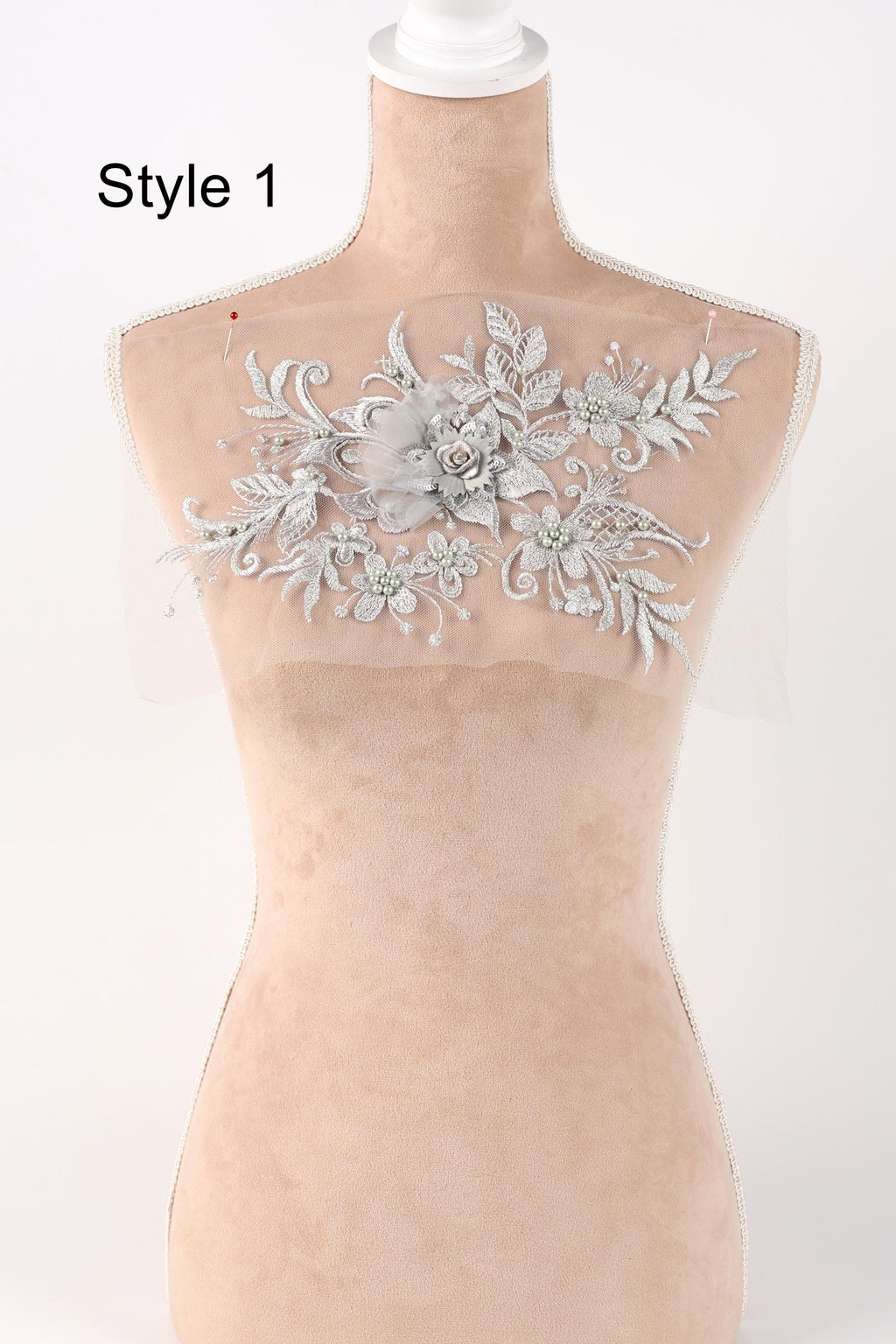 A mannequin with a decorative floral embroidery on its bust area, featuring a variety of white and silver floral designs.