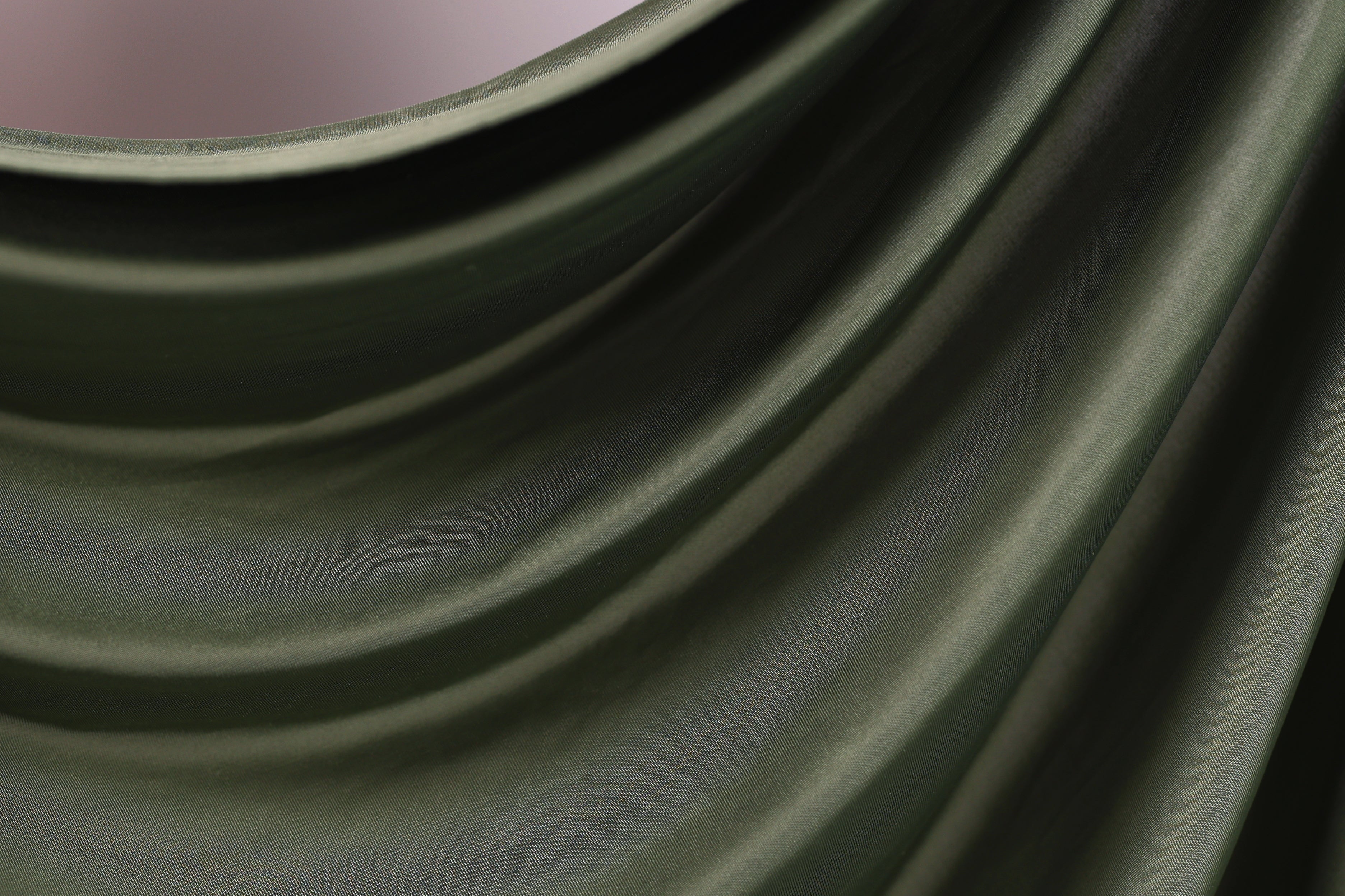The image is a close-up of a green fabric, possibly a piece of clothing or a textile. The fabric has a smooth, flowing texture and appears to be made of a shiny, shiny material. The image does not contain any discernible objects or actions, and there are no specific details provided about the color or pattern of the fabric.
