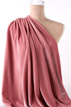 A mannequin wearing a pink velvet fabric draped over its shoulder.