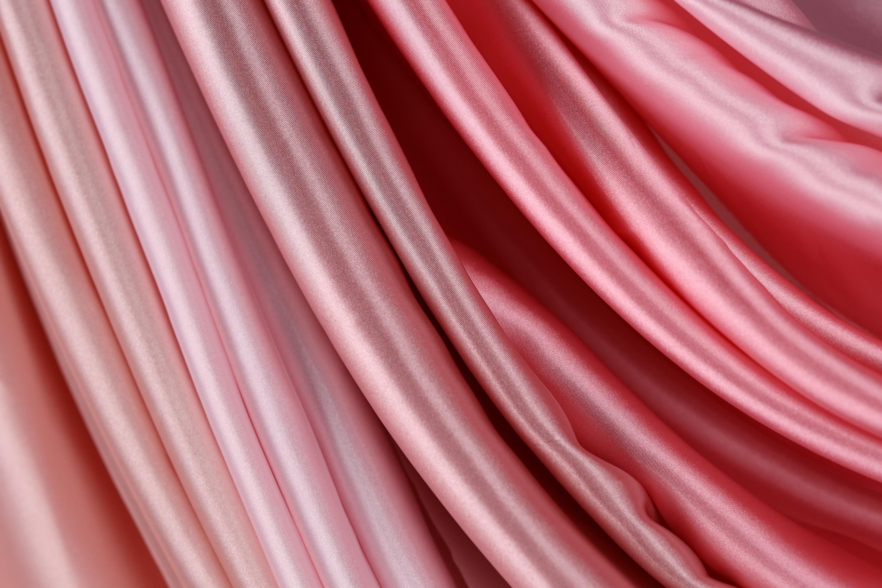 The image is a close-up of a fabric with a gradient of pink and red colors, creating a visually appealing and textured appearance.