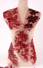 A mannequin wearing a red dress with intricate floral and lace patterns.