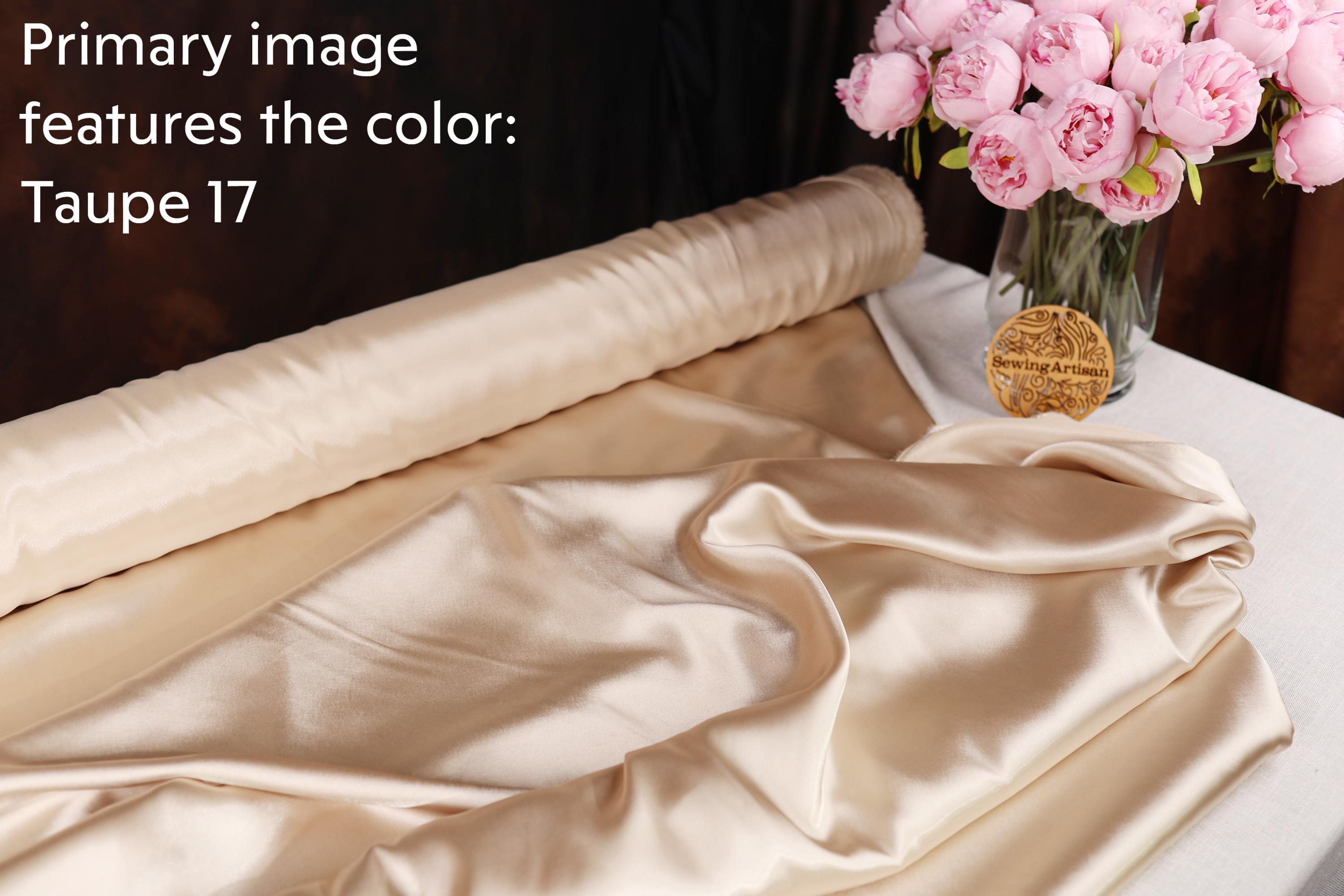 a roll of light-colored fabric, a vase of pink flowers, and a label on the vase.