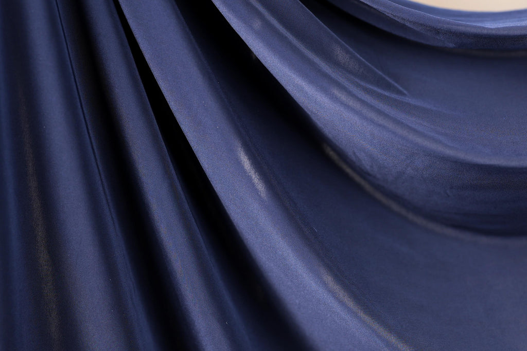 a close-up view of a dark blue fabric, possibly silk or chiffon, with a smooth and shiny texture.