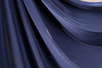 a close-up view of a dark blue fabric, possibly silk or chiffon, with a smooth and shiny texture.