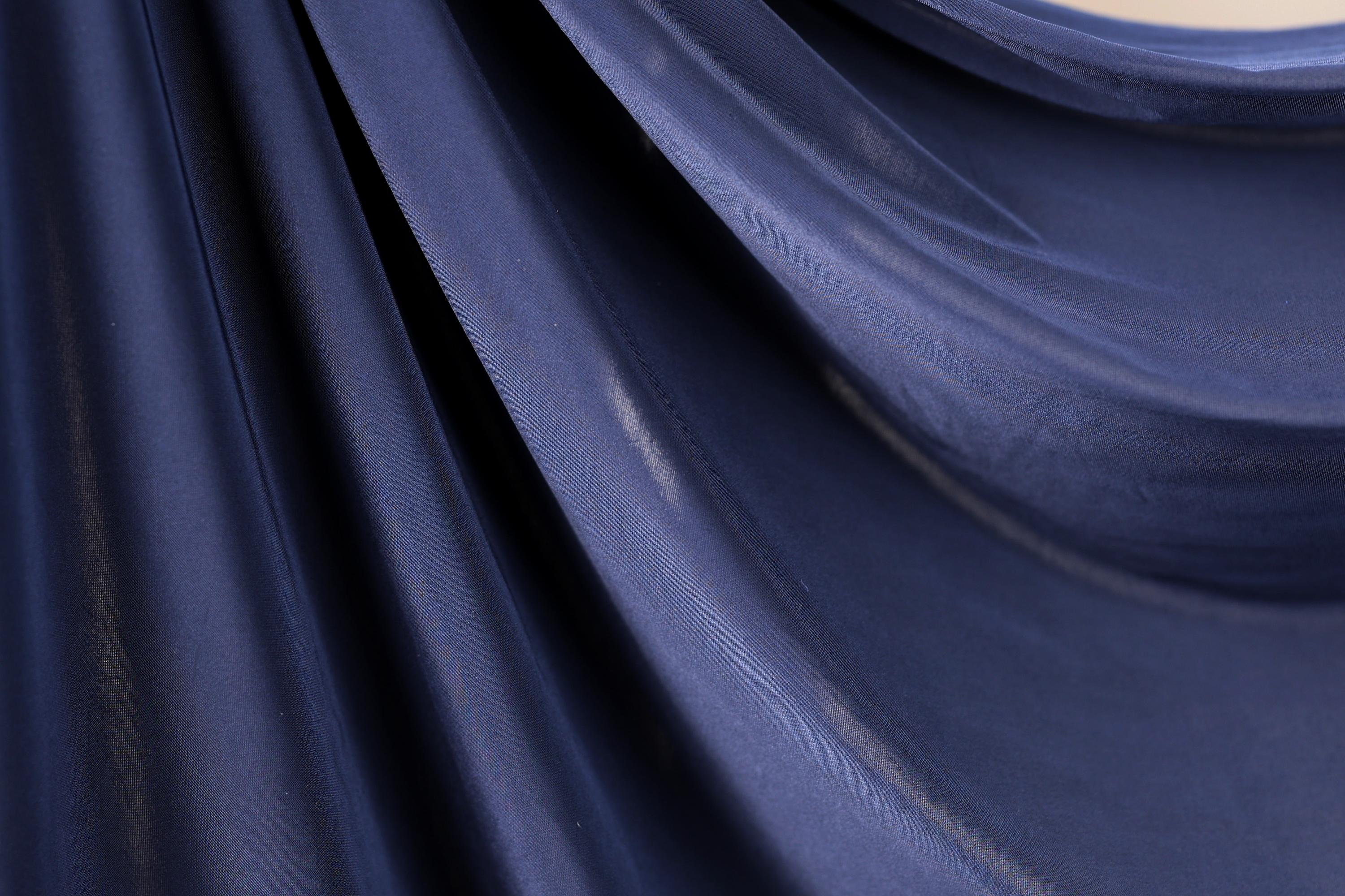 a close-up view of a dark blue fabric, possibly silk or chiffon, with a smooth and shiny texture.