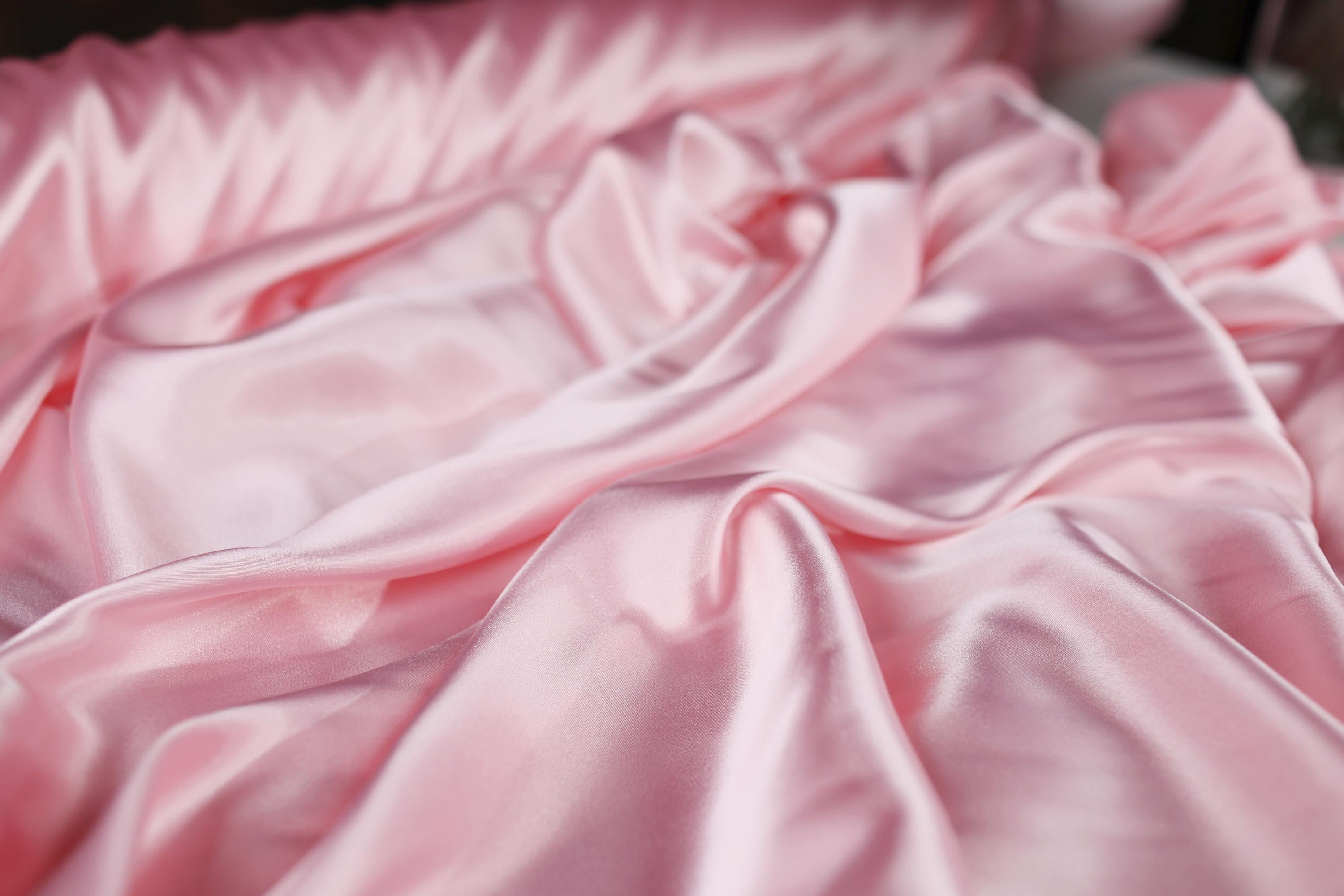 a close up of a bed with a pink comforter