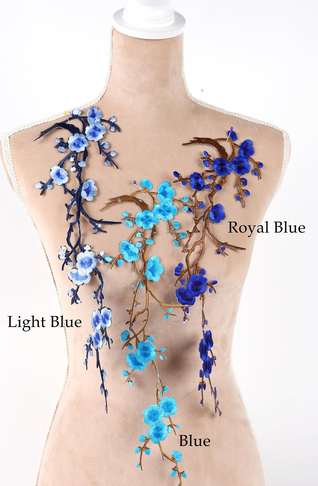 A mannequin torso with various blue floral embroidery designs on it, including light blue and royal blue flowers.