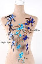 A mannequin torso with various blue floral embroidery designs on it, including light blue and royal blue flowers.