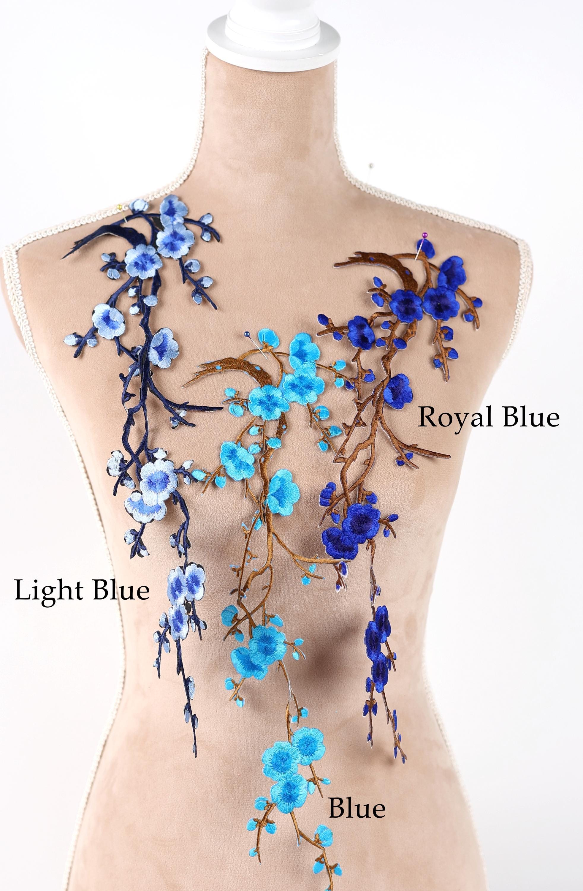 A mannequin torso with various blue floral embroidery designs on it, including light blue and royal blue flowers.