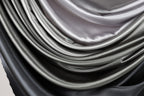 a close-up view of a pile of shiny, silky-looking fabric in shades of gray and black.