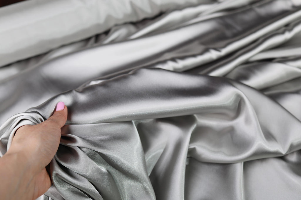 a person is holding a satin material in their hand