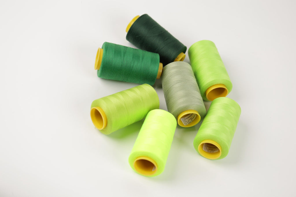 a collection of green and yellow spools of thread arranged on a white background.