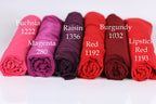 six rolled-up fabric swatches in various colors, including Fuchsia, Raisin, Burgundy, Magenta, Red, and Lipstick Red.