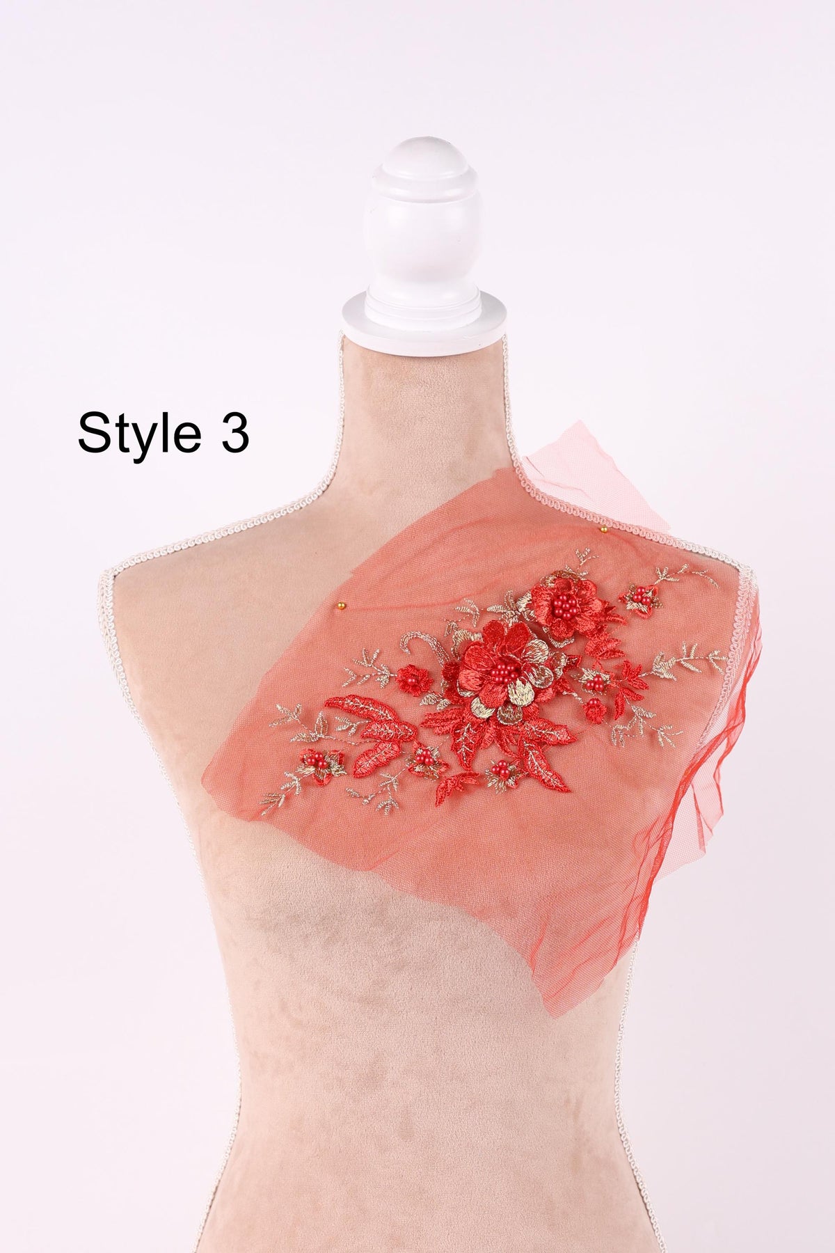 A mannequin with a red floral embroidered on its chest, wearing a white dress form.