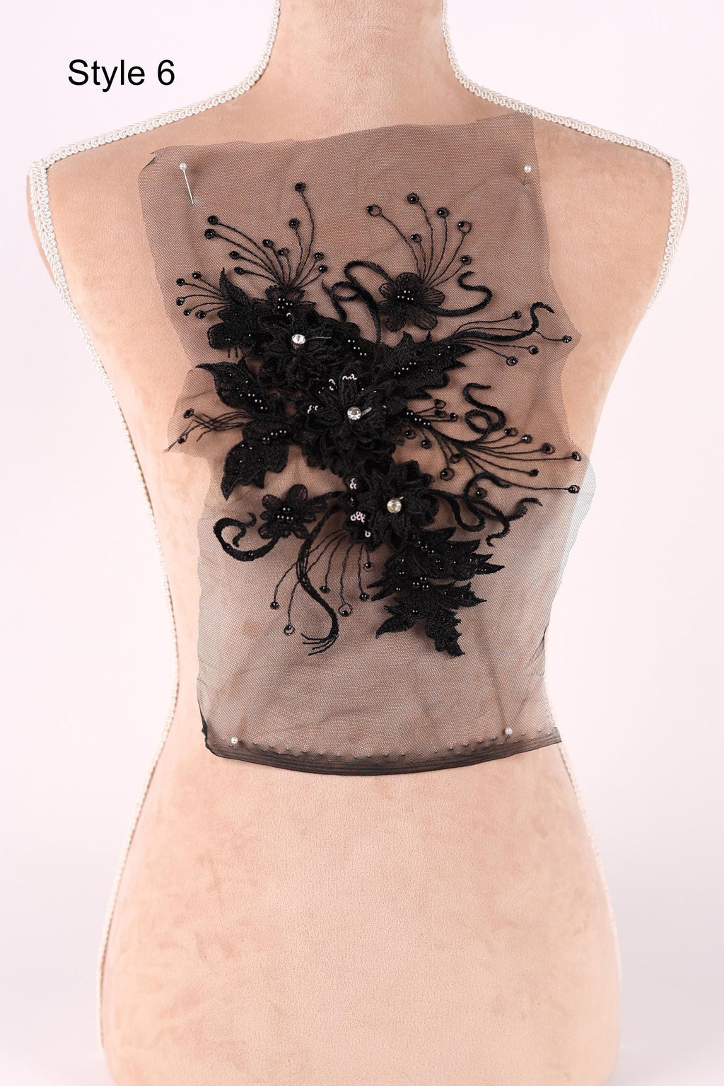 A mannequin with a decorative black lace piece on its back.