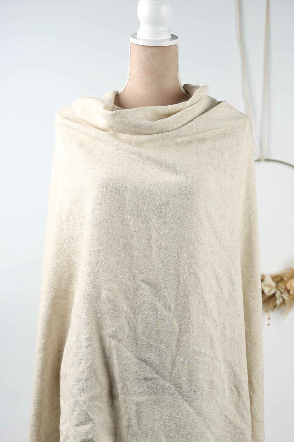 A mannequin wearing a beige fabric draped over its body.