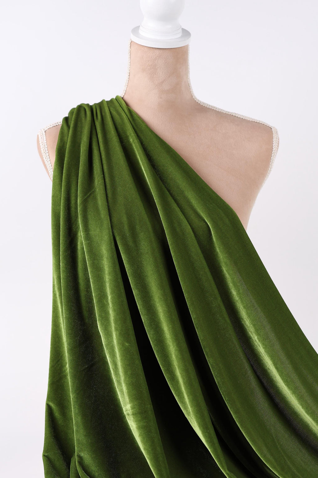 A close-up view of a green velvet fabric draped over a white object, creating a visually striking contrast.