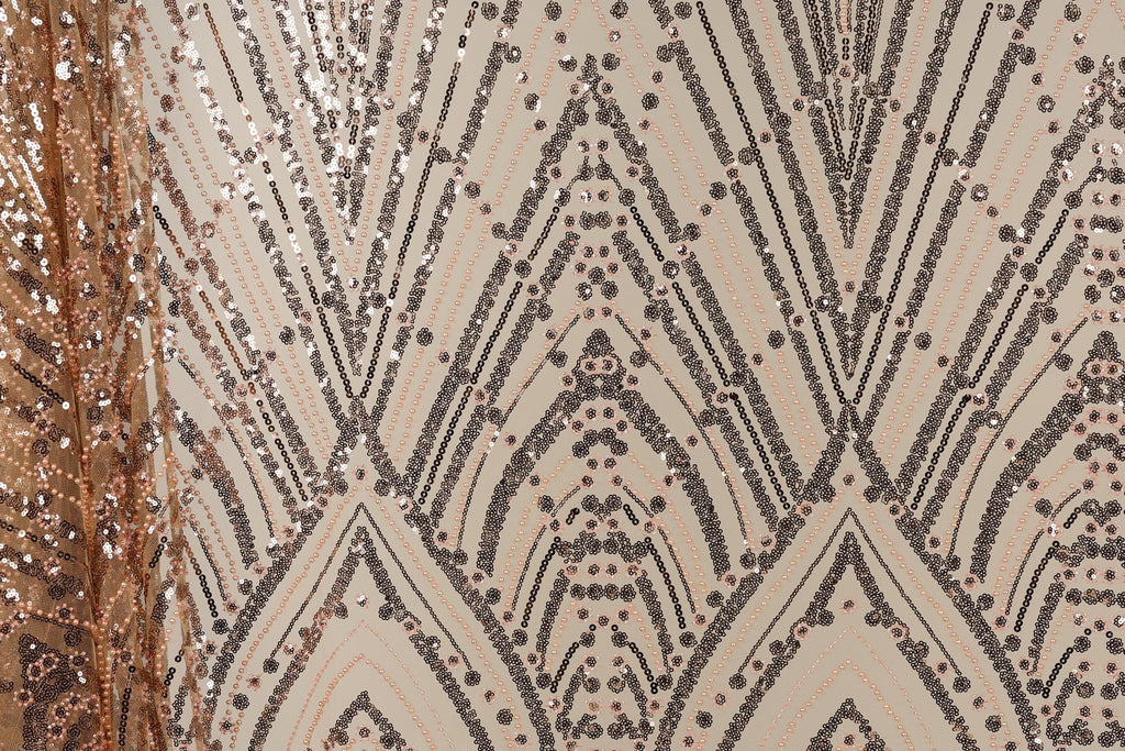a close-up view of a fabric with a repeating pattern of black and gold sequin designs. The pattern consists of diagonal lines and shapes, creating a visually striking and intricate design. The fabric appears to be a light-colored material, possibly beige or off-white, with the black and gold sequins adding a touch of sparkle and glamour.