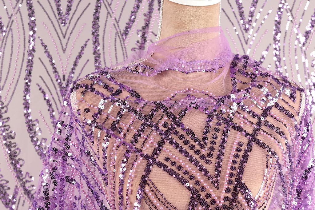 a mannequin wearing a purple sequin dress with a sheer, lace-like design. The dress has a pattern of purple and white sequins, and the mannequin is wearing a matching purple scarf.