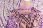 a mannequin wearing a purple sequin dress with a sheer, lace-like design. The dress has a pattern of purple and white sequins, and the mannequin is wearing a matching purple scarf.