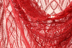 a close-up view of a red sequin fabric, with its intricate patterns and textures clearly visible.