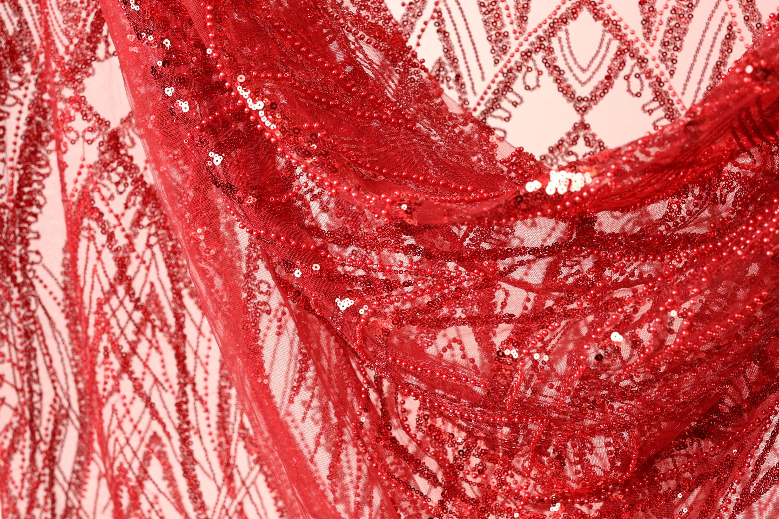 a close-up view of a red sequin fabric, with its intricate patterns and textures clearly visible.