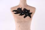 A mannequin with a decorative black lace piece on its chest.